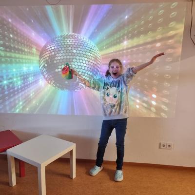 Ein Mädchen strahlt vor einer Diskokugel.