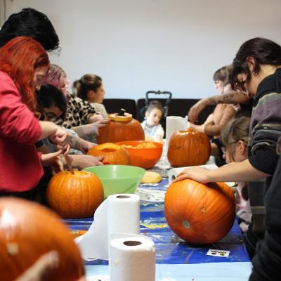 Kinder und Erwachsene schnitzen Kürbisse.