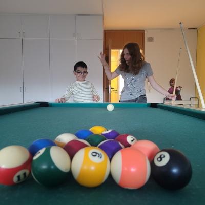 Zwei Kinder spielen eine Runde Billard. Die Kugeln sind groß im Vordergrund zu sehen.