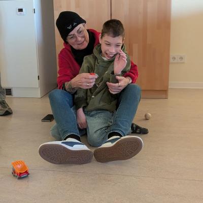 Auf dem Boden sitzen eine Frau und ein junge und lachen