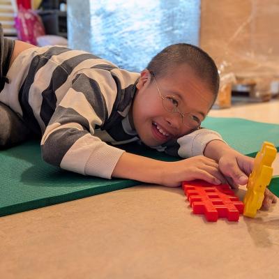 Ein Junge liegt auf dem Boden und lacht in die Kamera