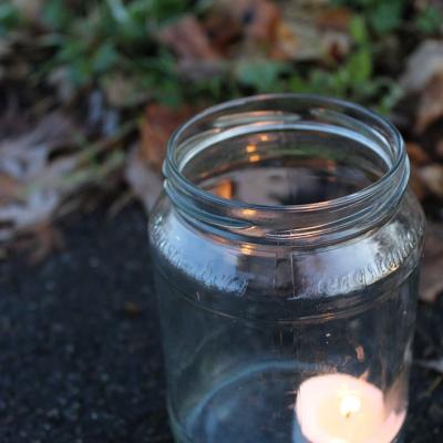 Ein brennendes Teelicht steht in einem Glas auf dem Boden