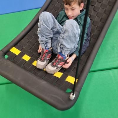 Ein Junge liegt in einer Schaukel und lacht.