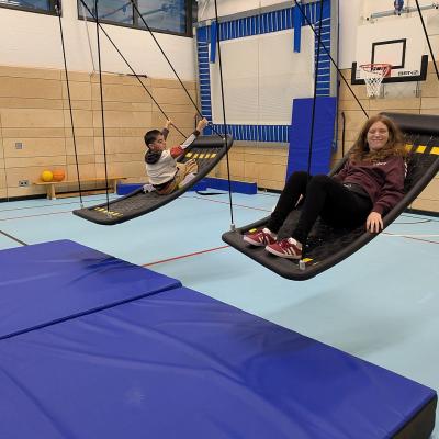 Ein Junge und ein Mädchen schaukeln auf zwei Netzschaukeln und haben Spaß