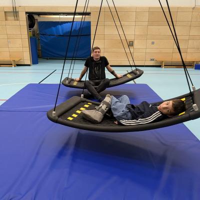 Ein junge und ein mann sitzen auf den Netzschaukeln und haben sichtlich Spaß