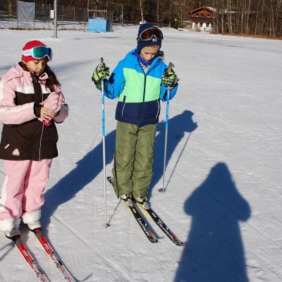 Sophia und Luca stehen mit Langlaufski im Schnee.