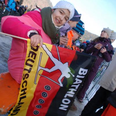 Ghofran lächelt in die Kamera und hält eine Deutschland-Flagge, auf der steht: 