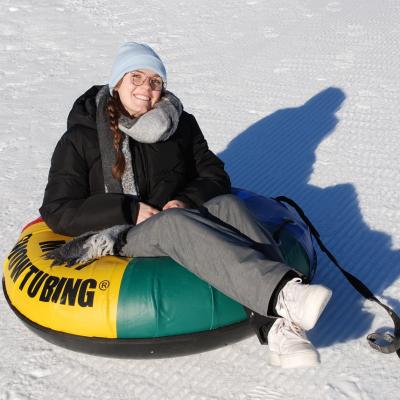 Lena sitzt in einem Reifen auf dem Schnee und lächelt in die Kamera.