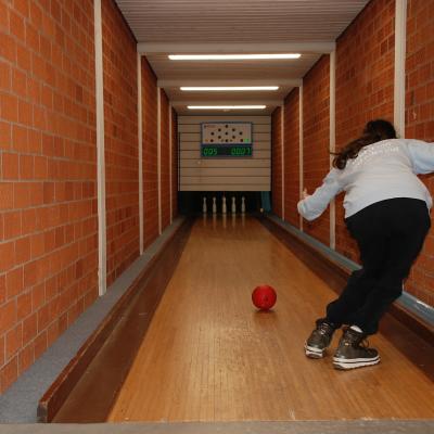 Auf der Kegelbahn hält sich Marija rechts an der Backsteinwand und rollt mir der linken Hand eine Kugel in Richtung Kegel. Diese stehen hinten unter einem Display.