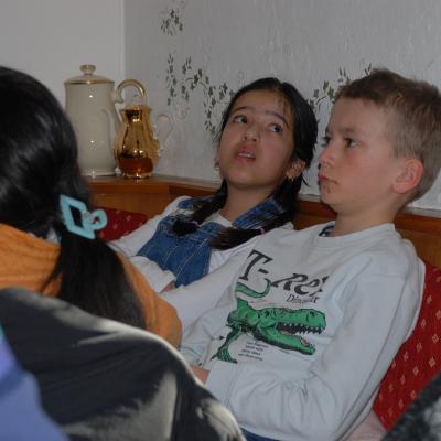 Ghofran und Luca lehnen sich auf der Eckbank nach hinten und schauen sich im Raum um.