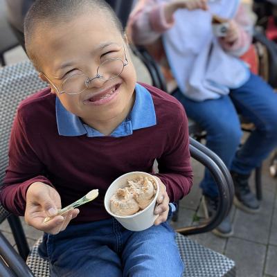 Ein junger Mann lacht in die Kamera und isst ein Eis.