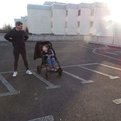 Ein Mann steht neben einem Jungen im Rollstuhl und lachen.