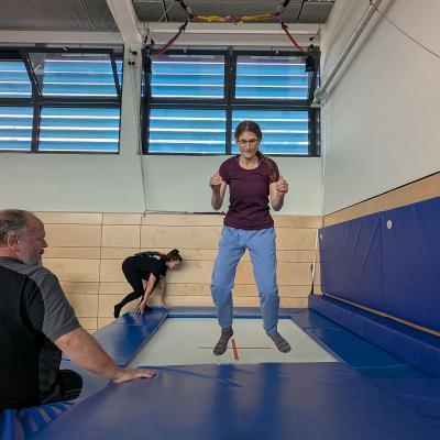 Eine Frau sprint auf dem Trampolin und ist in der Luft