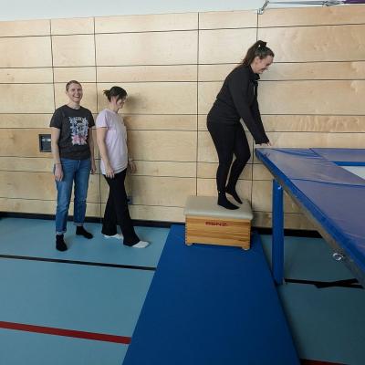 Drei Frauen stehen vor dem Trampolin, warten bis sie springen dürfen und lachen