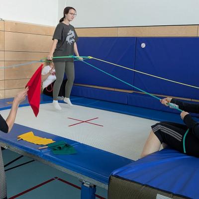 6 Frauen sind am Trampolin und machen eine Übung mit einem Hulahoop und Seilen