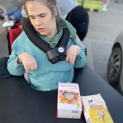 Eine junge Frau im Rollstuhl hat auf ihrem Tisch Müsli liegen