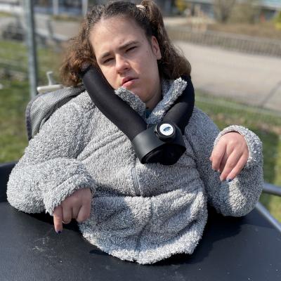 Eine junge Frau im Rollstuhl schaut in die Kamera