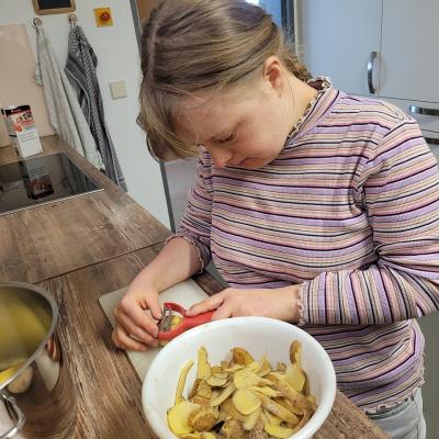 ein Mädchen schält Kartoffeln für den Salat