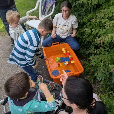 Eine Gruppe Kinder und eine Frau stehen beim Entenangelbecken und freuen sich