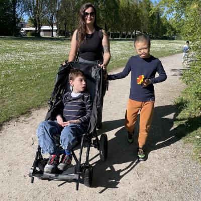 Eine Frau und zwei Jungen schauen in die Kamera, einer der Jungen sitzt im Rollstuhl
