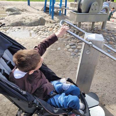 Ein Junge, der auf dem Spielplatz eine Wasserpumpe bedient.