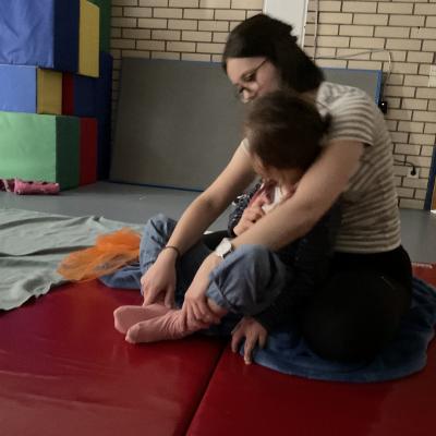 Eine Schülerin macht gemeinsam mit einer Lehrerin die Yoga-Übung „Schmetterling”.