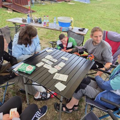 Ein Teil der Gruppe sitzt um den Tisch am Hüttenlager und spielt Karten.