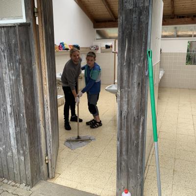 Zwei Teilnehmer putzen den Waschraum mit dem Bodenwischer.