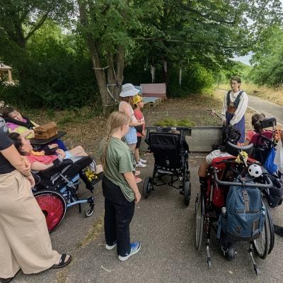 Eine Gruppe mit Frauen und Kinder stehen zusammen und hören der Geschichtenerzählerin zu