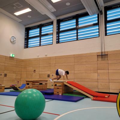 Ein Junge, der in der Sporthalle über einen Parkour klettert. 